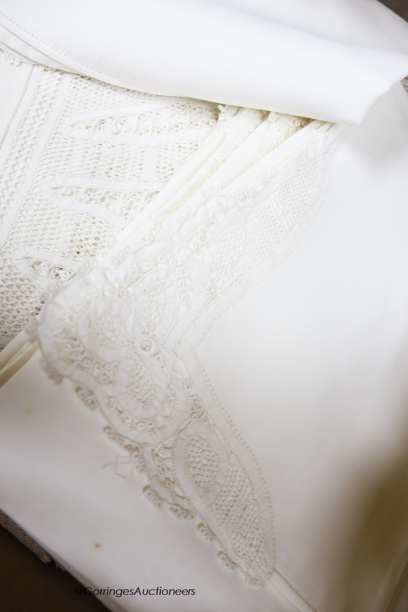 A finely worded tapelace and cutwork white tablecloth with matching serviettes and a similar ecru table cover